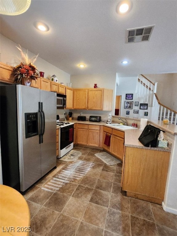 kitchen with sink, white gas stove, stainless steel fridge with ice dispenser, and kitchen peninsula