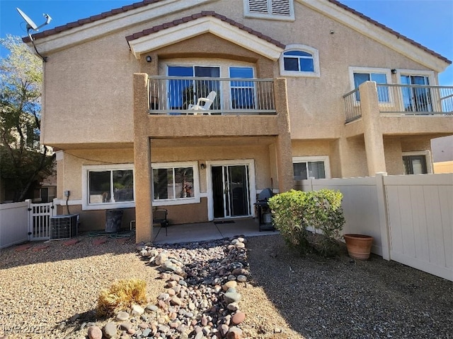 rear view of property featuring cooling unit, a balcony, and a patio area