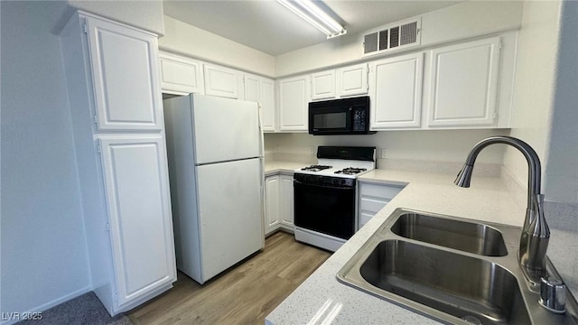 kitchen with white cabinetry, sink, white fridge, light hardwood / wood-style floors, and gas range