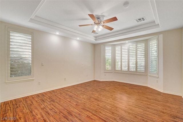 unfurnished room featuring hardwood / wood-style floors, a raised ceiling, and ceiling fan