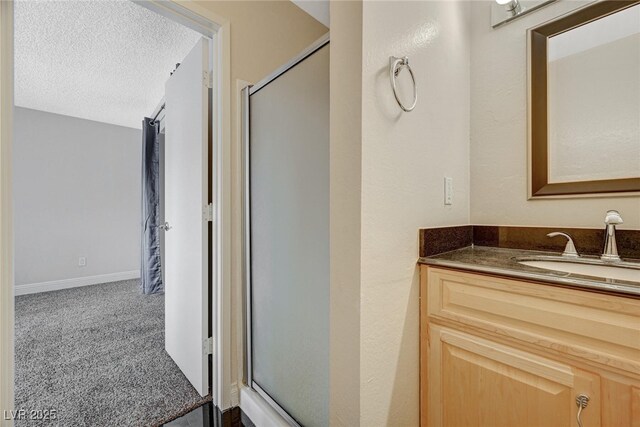 bathroom with a shower with door, vanity, and a textured ceiling