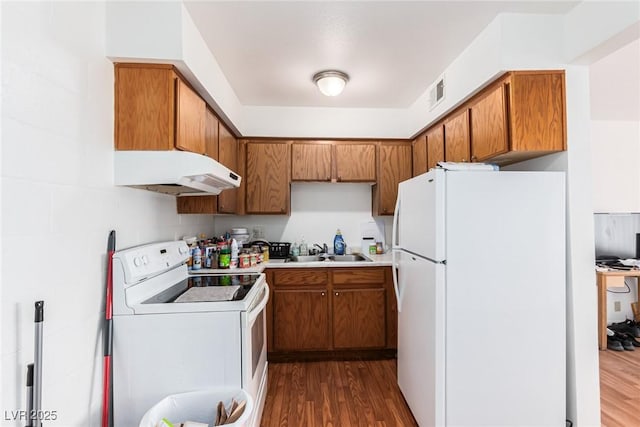 kitchen with white appliances, dark hardwood / wood-style flooring, washer / clothes dryer, and sink