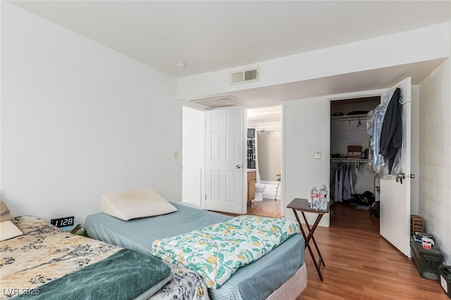 bedroom featuring hardwood / wood-style flooring, a walk in closet, ensuite bath, and a closet