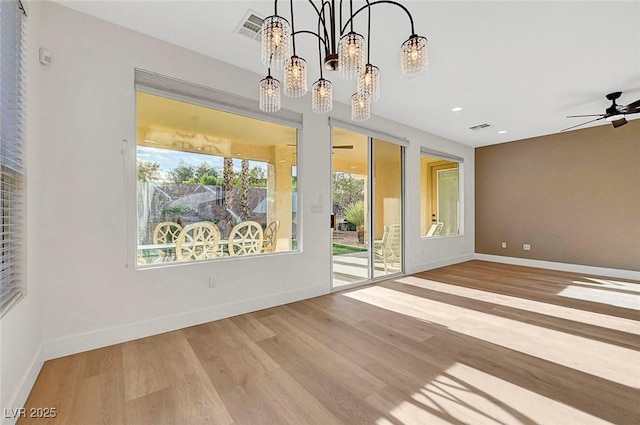 interior space with ceiling fan with notable chandelier and light hardwood / wood-style floors