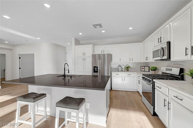 kitchen with sink, a center island with sink, white cabinets, and appliances with stainless steel finishes