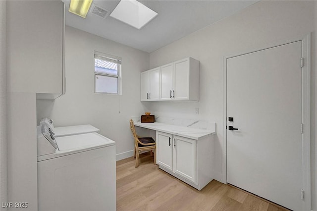 laundry room with sink, a skylight, cabinets, light hardwood / wood-style floors, and washing machine and clothes dryer