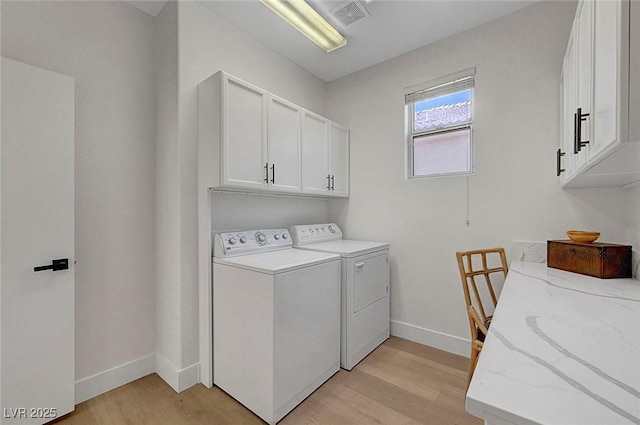 laundry room featuring cabinets, washer and clothes dryer, and light wood-type flooring