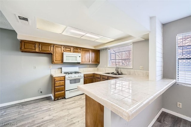 3954 Edgemoor Way, Las Vegas, NV 89121 - kitchen with white appliances, brown cabinets, a peninsula, and light wood-style flooring