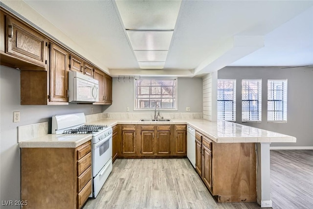 3954 Edgemoor Way, Las Vegas, NV 89121 - kitchen with white appliances, a peninsula, light wood-type flooring, and brown cabinetry