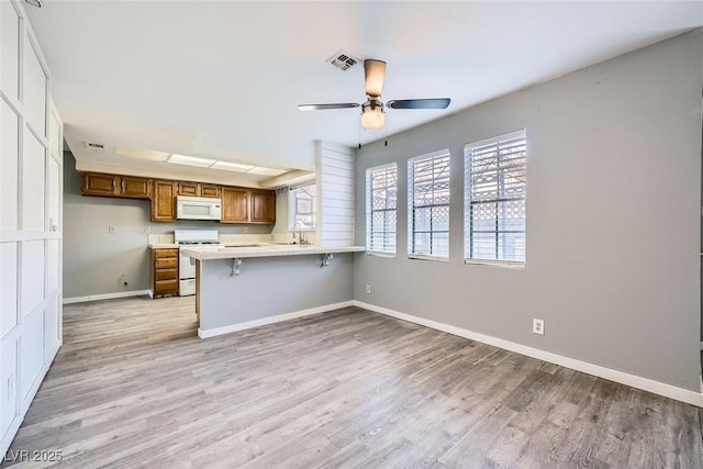 3954 Edgemoor Way, Las Vegas, NV 89121 - kitchen with white appliances, ceiling fan, brown cabinets, light countertops, and light wood-style flooring
