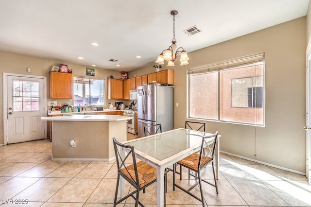 kitchen featuring pendant lighting, light tile patterned floors, white appliances, a notable chandelier, and a kitchen island