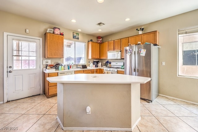 kitchen with light tile patterned flooring, white appliances, and a center island