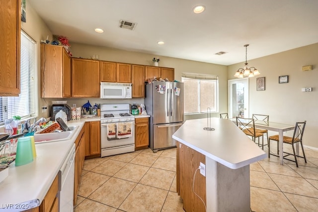 kitchen with pendant lighting, light tile patterned floors, white appliances, and a kitchen island