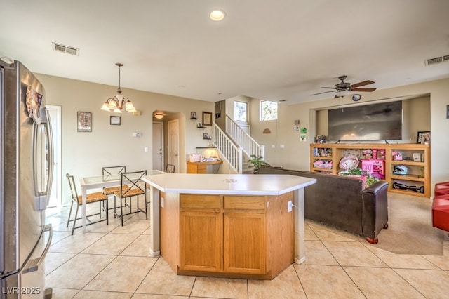 kitchen with light tile patterned flooring, a kitchen island, pendant lighting, and stainless steel refrigerator