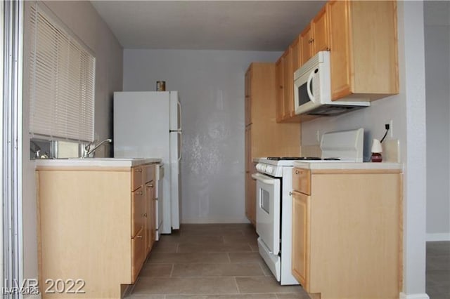 kitchen with white appliances, light brown cabinetry, and sink