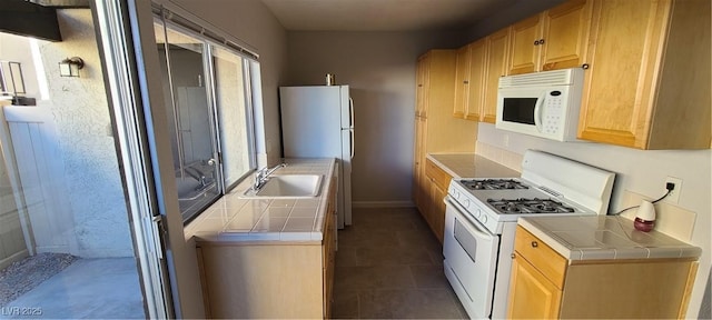 kitchen with a healthy amount of sunlight, sink, tile countertops, and white appliances