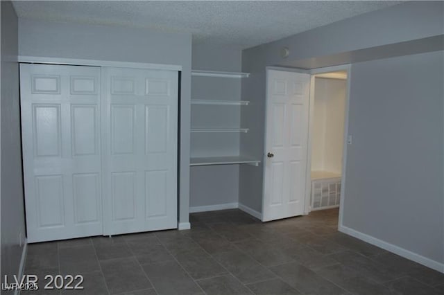 unfurnished bedroom featuring a textured ceiling and a closet