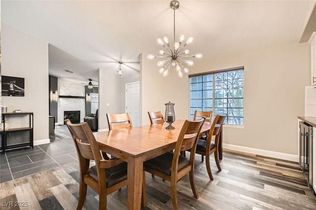 dining room with dark hardwood / wood-style floors, a fireplace, and ceiling fan with notable chandelier