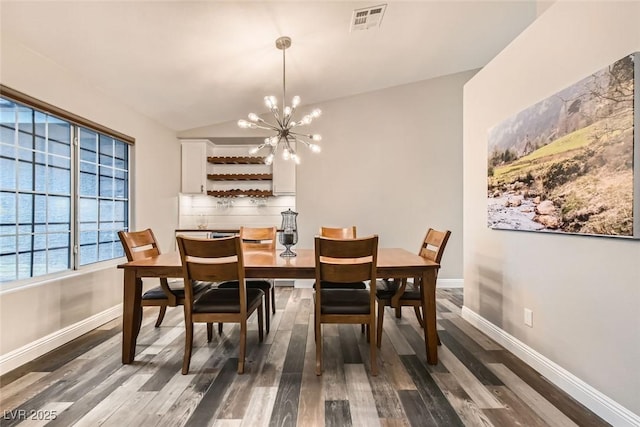 dining space featuring lofted ceiling, dark hardwood / wood-style floors, and a chandelier