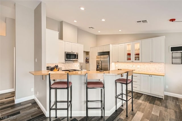 kitchen featuring lofted ceiling, stainless steel appliances, a breakfast bar, and white cabinets