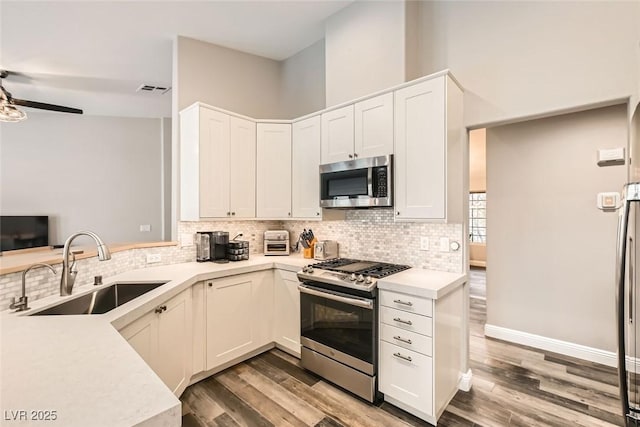 kitchen with sink, kitchen peninsula, stainless steel appliances, decorative backsplash, and white cabinets