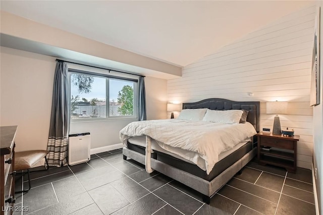 bedroom with lofted ceiling, wooden walls, and dark tile patterned floors