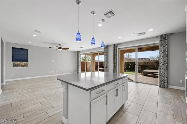 kitchen featuring ceiling fan, decorative light fixtures, white cabinets, and a kitchen island