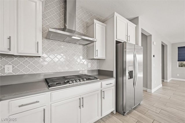 kitchen with white cabinetry, stainless steel appliances, tasteful backsplash, and wall chimney range hood