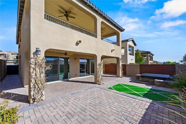 rear view of house with ceiling fan, a patio area, and a balcony