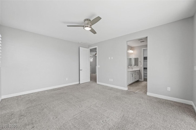 unfurnished bedroom featuring connected bathroom, light colored carpet, and ceiling fan