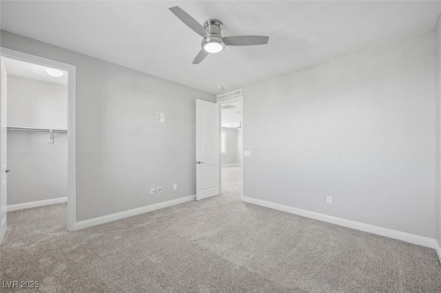 unfurnished bedroom with a walk in closet, carpet floors, ceiling fan, and a closet