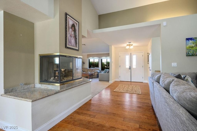 entryway with hardwood / wood-style flooring, a multi sided fireplace, and a high ceiling