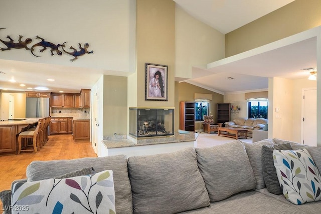 living room featuring crown molding, high vaulted ceiling, and light wood-type flooring