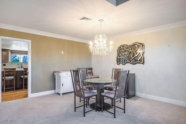 carpeted dining room featuring ornamental molding and an inviting chandelier