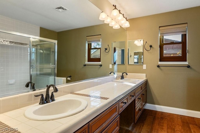 bathroom with vanity, hardwood / wood-style floors, a shower with door, and a chandelier