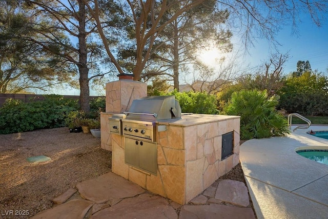 view of patio / terrace featuring a grill, a fenced in pool, and an outdoor kitchen