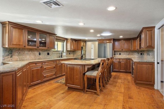 kitchen featuring stainless steel refrigerator, a kitchen breakfast bar, a center island, and light wood-type flooring