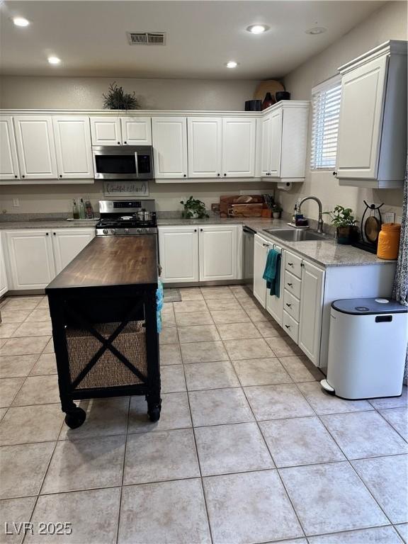 kitchen with stainless steel appliances, white cabinetry, sink, and light tile patterned floors