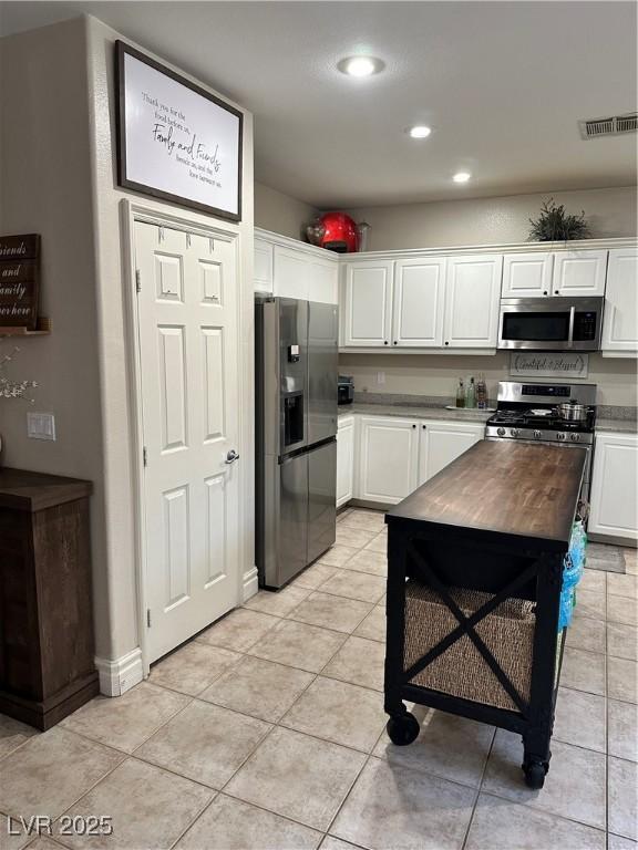 kitchen featuring white cabinetry, appliances with stainless steel finishes, butcher block counters, and light tile patterned floors