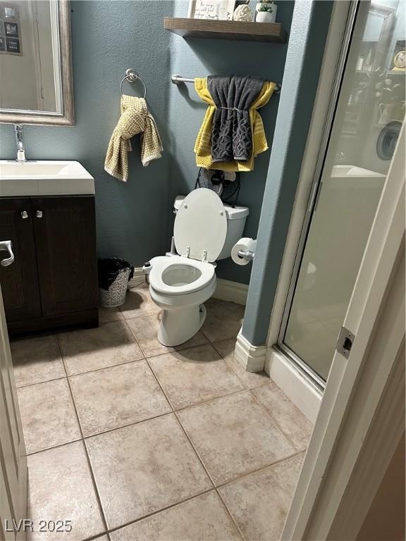 bathroom featuring toilet, vanity, tile patterned floors, and walk in shower