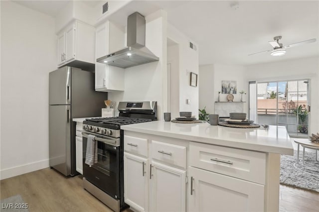 kitchen with white cabinets, exhaust hood, ceiling fan, light hardwood / wood-style floors, and stainless steel appliances