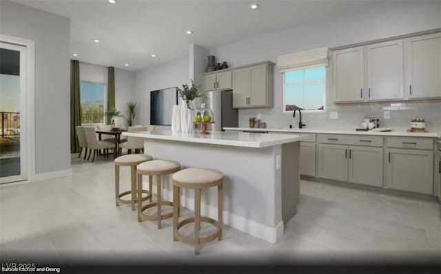 kitchen featuring gray cabinetry, sink, stainless steel fridge, and a kitchen island