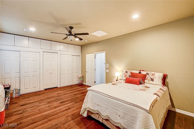 bedroom featuring ceiling fan, hardwood / wood-style flooring, and multiple closets