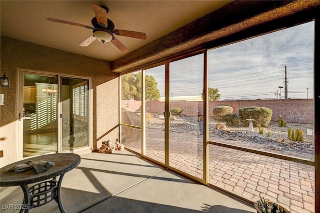 sunroom / solarium featuring ceiling fan with notable chandelier