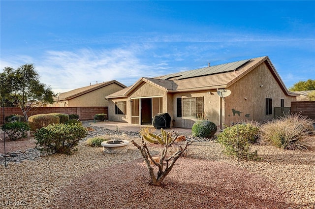 back of property featuring a patio area, solar panels, and an outdoor fire pit