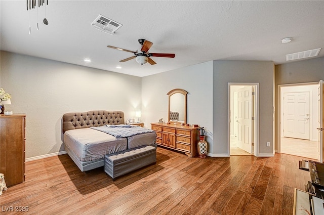 bedroom with ceiling fan, hardwood / wood-style flooring, and a textured ceiling