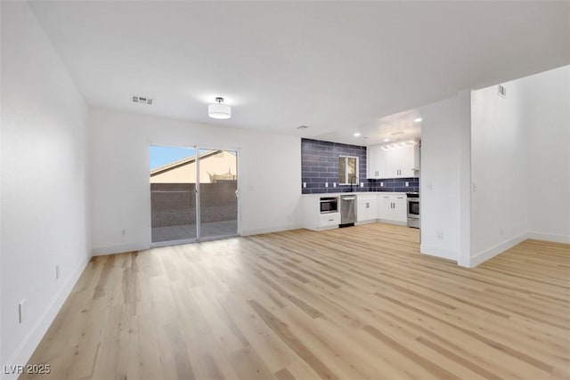 unfurnished living room featuring sink and light wood-type flooring