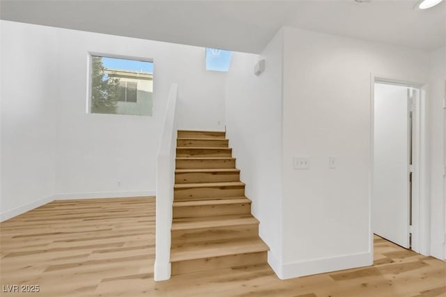 stairway with a skylight and hardwood / wood-style floors