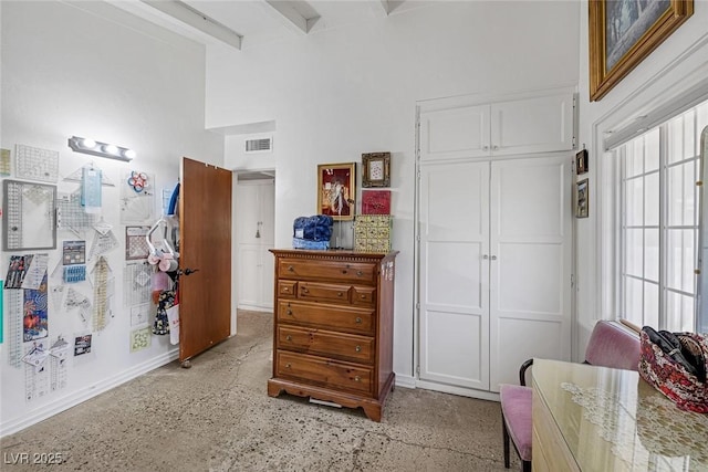 interior space featuring beamed ceiling, a high ceiling, and a closet