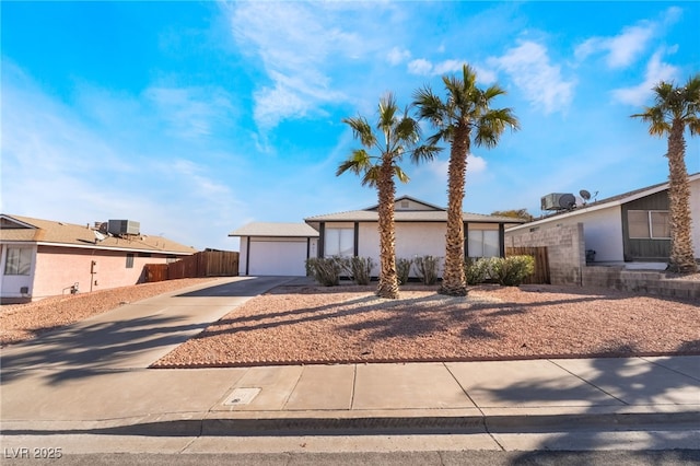 view of front of property with an attached garage, cooling unit, fence, driveway, and stucco siding